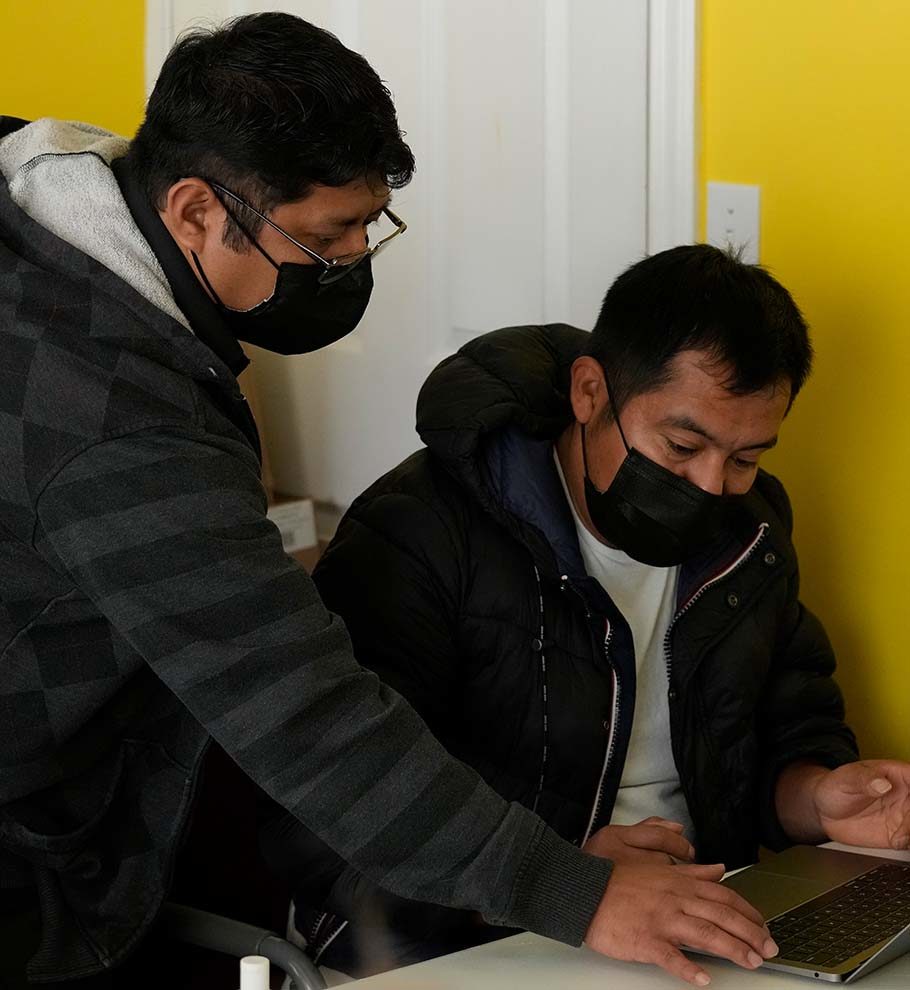 two men in black face masks working at a computer together